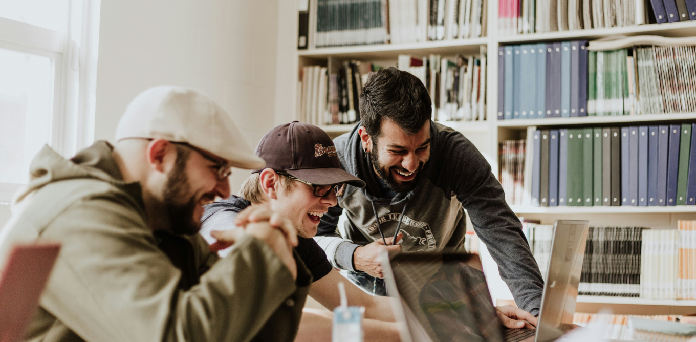 Three members of a team gathered around a laptop, smiling